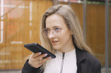 Happy girl records an audio message on a smartphone.