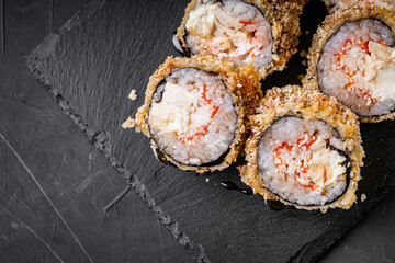 delicious sushi rolls on a black stone background