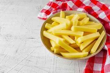 peeled potatoes sliced for french fries on a white background