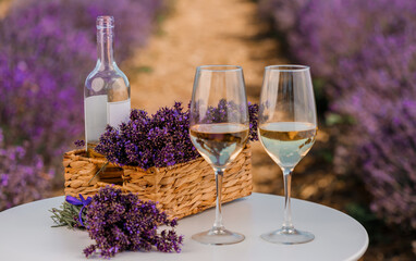Two Glasses of white wine and bottle in a lavender field in Provance. Violet flowers on the background - 519227403
