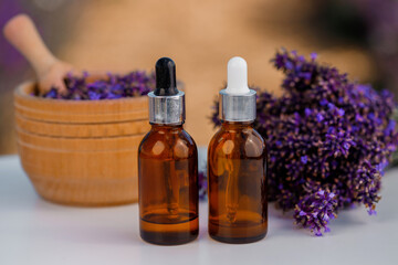 Dropper bottle with lavender cosmetic oil or hydrolate against lavender flowers field as background with copy space. Herbal cosmetics and modern apothecary concept