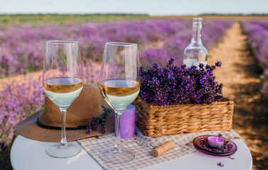 Two Glasses of white wine and bottle in a lavender field in Provance. Violet flowers on the background