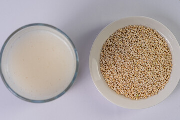 Quinoa bowl and quinoa drink on a glass, on a white table, top view