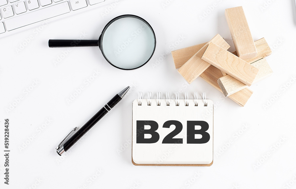 Poster b2b word written on notebook with block magnifier and pen , business concept.