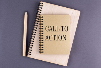 Word CALL TO ACTION on a notebook with pencil on the grey background