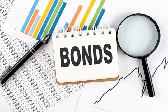 BONDS text on notebook on the graph background with pen and magnifier