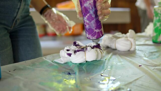 Painting of a white Tshirt with the help of purple paint. Staining Tshirts with your own hands Tie Dye. Video close -up of a person s hands.