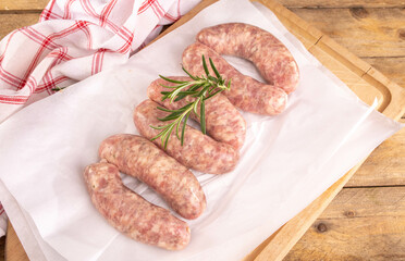 Traditional raw white sausage on a paper, on a wooden background. Composition with white sausage, easter delicacy.