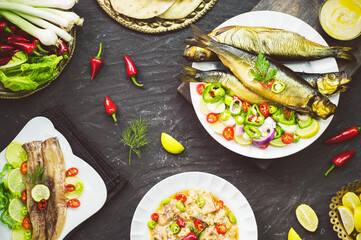 Mediterranean food, Smoked Herring fish served with green onion, lemon, chili pepper, lettuce, spices, pita bread and tahini sauce. Top view with close-up.