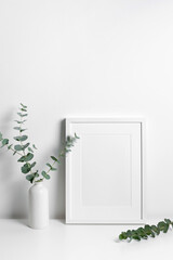 White portrait frame mockup with green eucalyptus twig decoration
