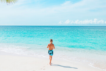 cute boy run along the beach in the Maldives, a travel concept