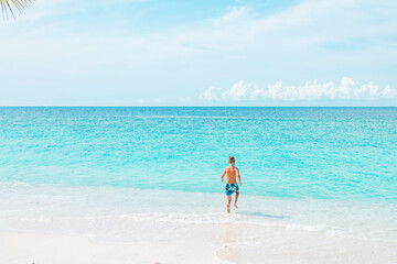cute boy run along the beach in the Maldives, a travel concept