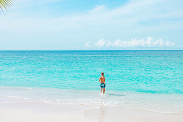 Fototapeta na wymiar cute boy run along the beach in the Maldives, a travel concept