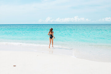 Fototapeta na wymiar teenage girl with red hair in swimsuit run along the beach in the Maldives, a travel concept
