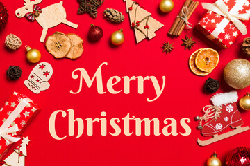Fototapeta na wymiar Merry Christmas text. Top view of Christmas decorations on red background. New Year holiday concept with copy space