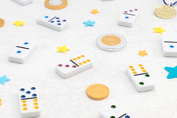 White dominoes with colorful dots,winner medal and chocolate coins on white cement background. Board game.