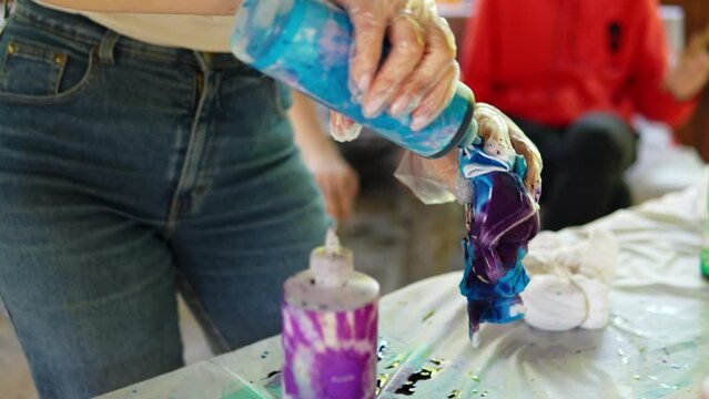 Painting of a white T -shirt with blue paint. Staining T -shirts with your own hands Tie Dye video close -up of a person s hands.