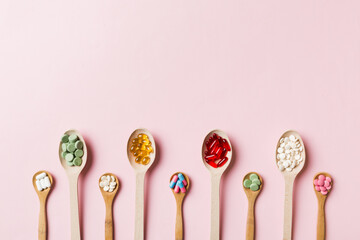 Top view Variety of vitamin and mineral pills in wooden spoon on Colored background. Top view of assorted pharmaceutical medicine pills. Dietary supplement healthcare product