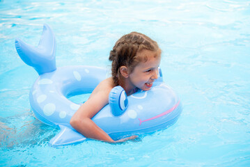Fototapeta na wymiar A little girl bathes in the pool. Summer. Vacation.