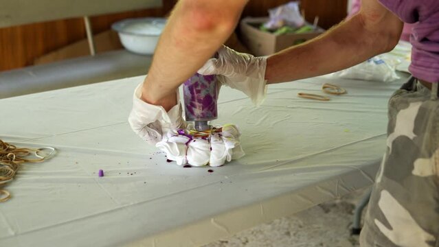 Painting of a white Tshirt with the help of purple paint. Staining Tshirts with your own hands Tie Dye. Video close -up of a person s hands.