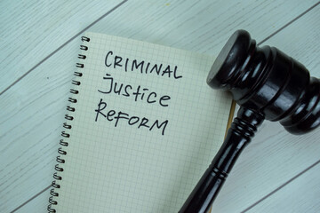 Concept of Criminal Justice Reform write on a book with gavel isolated on Wooden Table. - obrazy, fototapety, plakaty