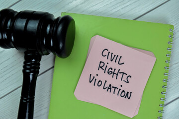 Concept of Civil Rights Violation write on sticky notes with gavel isolated on Wooden Table.