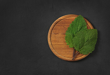 sage leaves on a cutting board on dark background,copy space, top view