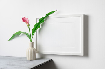 Horizontal picture frame mockup over white wall with calla flowers