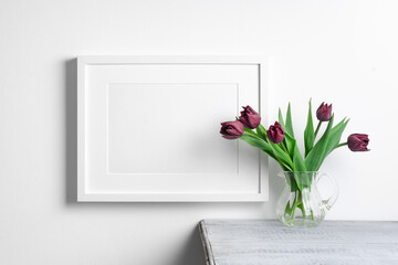 White landscape frame mockup over white wall with tulips flowers bouquet