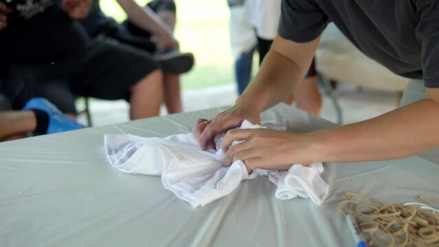 The girl collects a T -shirt in a stain for staining. Staining T -shirts with your own hands Tie. Close -up video Human hands.