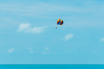 Fototapeta na wymiar Rainbow parachute on the background of the blue sea and sky. Landscape. Summer. Vacation.
