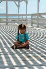 A little girl in the shade of a gazebo plays with stones. She plays of light and shadow. Childhood.