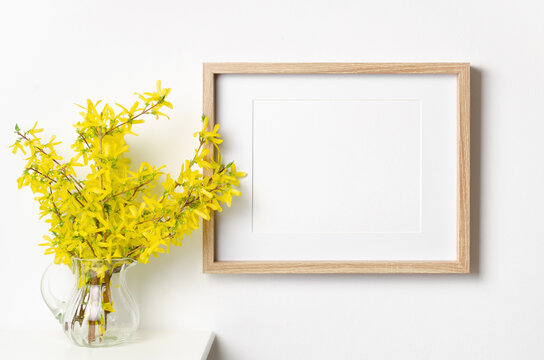Blank frame mockup in white interior with yellow flowers