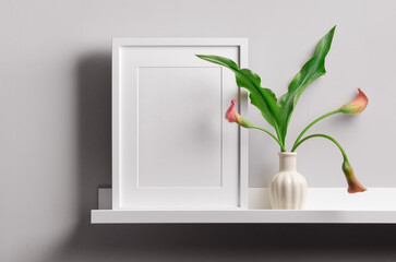 Portrait frame mockup on shelf with calla flowers for artwork or print presentation