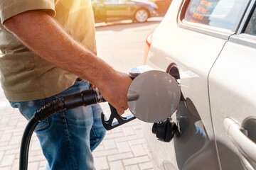 A man at the gas station filling the tank of his car with diesel to the top level before a long...