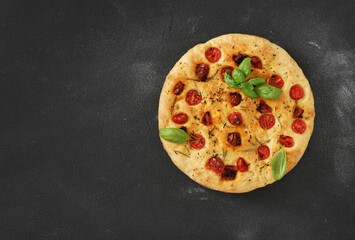 Traditional Italian Focaccia with tomatoes and rosemary on the dark background - homemade. Copy space.
