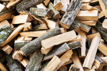Stock of firewood for heating the house. The trees were cut down and split into firewood for use as fuel in fireplaces and stoves, with a background of firewood.