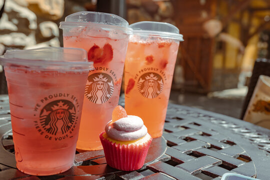 Waterton, Alberta, Canada - July 5, 2022: Strawberry Acai refresher beverages and a cupcake placed outside on a picnic table in the summer