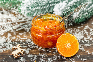 Organic orange jam with snow-covered fir branches. Seasonal food, handmade gift, traditional dessert