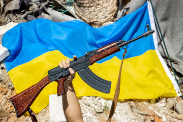 The raised gun in front of Ukrainian flag on ruins
