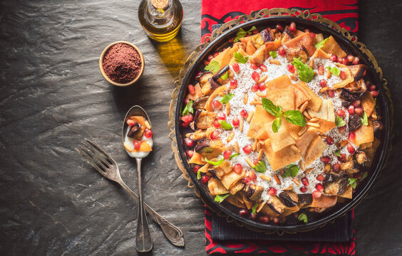 Arabic Cuisine;Traditional Middle Eastern dish "Eggplant Fatteh".This is a delicious mix of toasted pieces of pita bread and fried aubergine. Topped with garlicky-tahini sauce,pomegranate and pine nut