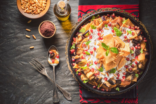 Arabic Cuisine;Traditional Middle Eastern dish "Eggplant Fatteh".This is a delicious mix of toasted pieces of pita bread and fried aubergine. Topped with garlicky-tahini sauce,pomegranate and pine nut