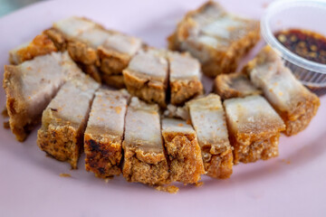 Selective focus, sliced crispy belly pork served on pink plate.
