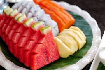 Mix various slice of tropical fruit on banana leaf and white plate. 