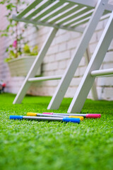 MYK marker pens on grass floor in the garden with two white chairs
