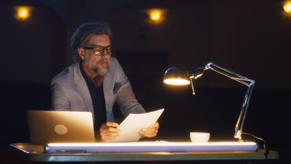The director in the dark theater reading the script and giving recommendations to the actors,...