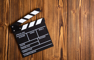 black movie clapper with white inscriptions on a wooden table