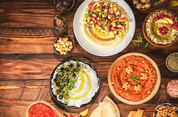 Arabic Cuisine: Varieties of delicious Middle Eastern meze and dips. hummus plate, muhammara, labneh, baba ghanough, harissa and olives. Served with pita bread and fresh olive oil.