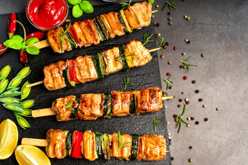 .Chicken shish kebab with zucchini. Top view.Grilled pieces of chicken meat on skewers.Grilled chicken kebab with vegetables on a black background