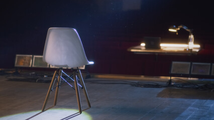 After a rehearsal the director's chair standing on a dim stage illuminated by a spotlight in a...